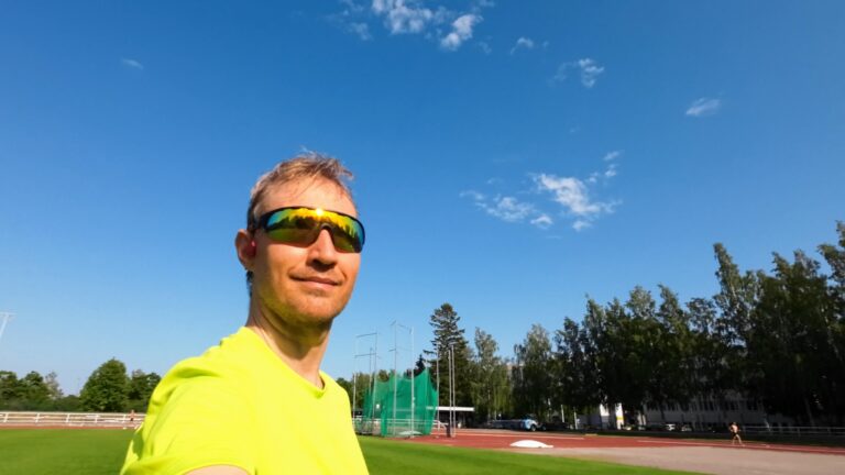 Lenni Laukkanen urheilukentällä. Sininen taivas, vihreä nurmikko ja juoksurata.
